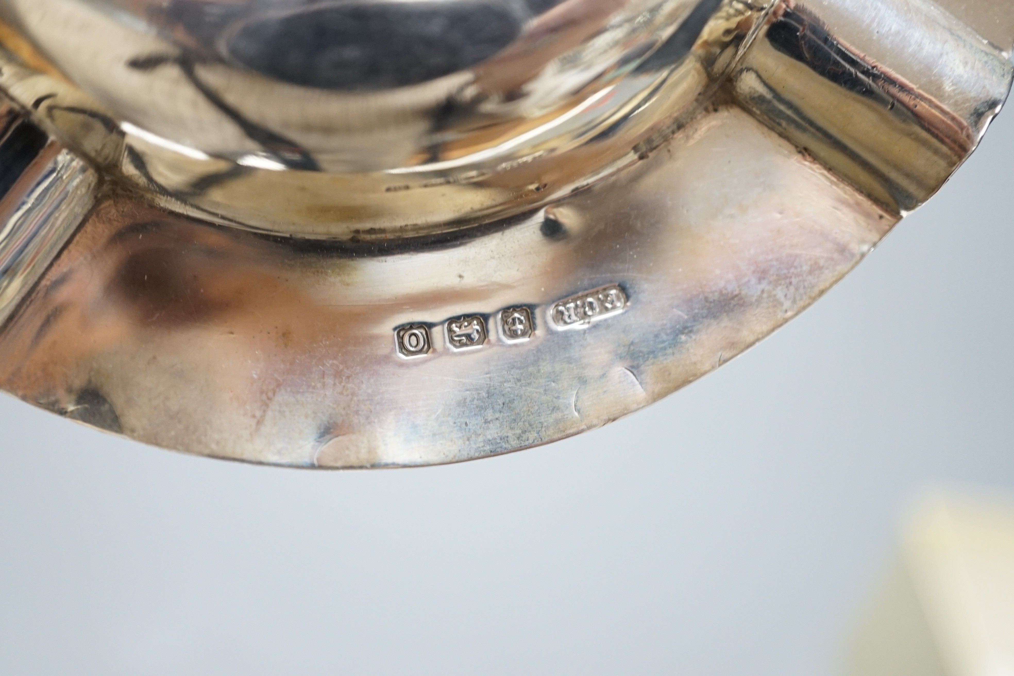 A late Victorian silver mustard pot, Sheffield, 1896, a later silver ashtray and small bowl and an Edwardian pieced silver shaped dish by Elkington & Co, London, 1909.